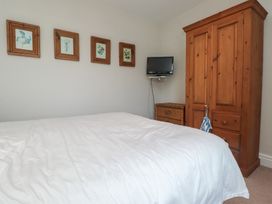 A bedroom with a bed, wardrobe, television, and framed artwork at Bryniau in Pwllheli