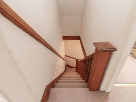 A staircase with wooden handrail and carpet at Bryniau Pwllheli