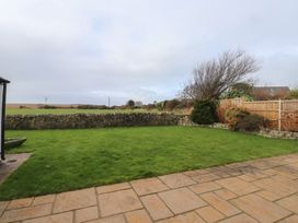 A garden with grass and stone wall at Bryniau in Pwllheli