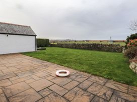 A garden with grass and stone paving at Bryniau Pwllheli