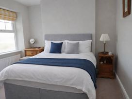 A bedroom with a bed, bedside table and lamp at Bryniau in Morfa Nefyn