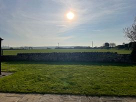 A sunny view of a field and stone wall at Bryniau in Morfa Nefyn