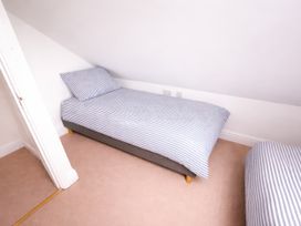 A bedroom with two beds and a door at Bryniau, Morfa Nefyn