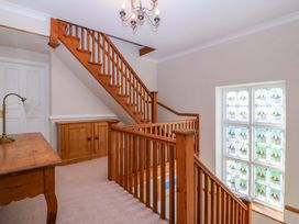 A staircase with wooden handrail and stained glass window at Bryniau Morfa Nefyn