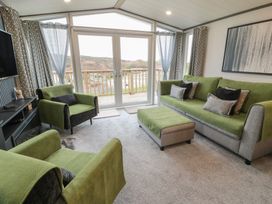 A living room with green furniture and a view at Willow's Way in Stranraer