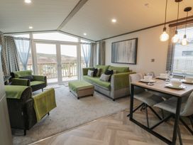 A living room with a sofa and dining area at Willow's Way in Stranraer