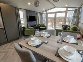A living room with a table set and a television at Willow's Way in Stranraer