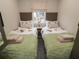 A bedroom with two beds and a bedside table at Willow's Way in Stranraer