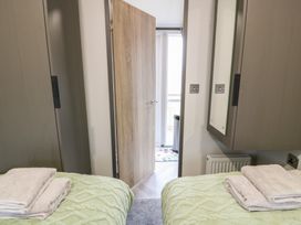 A bedroom with beds and a door leading to another area at Willow's Way in Stranraer