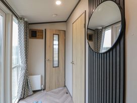 A hallway with a door and mirror at Willow's Way in Stranraer