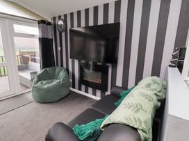 A living room with a television and a bean bag at Harper's Hideaway, Felmoor Holiday Park near Felton