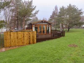 A cabin with a deck and wooden fence at Harper's Hideaway near Felmoor Holiday Park near Felton