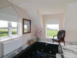 A bathroom with a bathtub and a chair at Ard Uisce @ Estuary Bliss, Duncannon, County Wexford
