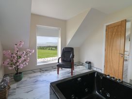 A room with a chair, window, and jacuzzi at Ard Uisce @ Estuary Bliss, Duncannon, County Wexford
