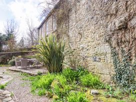 A garden with a stone wall and patio furniture at The Mill House in Newton Abbot
