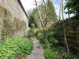 A garden with a gravel path and stone wall at The Mill House in Newton Abbot