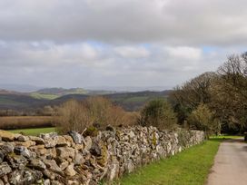 A stone wall along a road with hills and trees at The Mill House in Newton Abbot