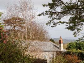 A view of a house with a chimney and surrounding trees at The Mill House in Newton Abbot