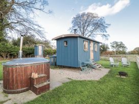 An outdoor area with a hot tub and a blue cabin at Honeysuckle Hut, Potto Grange Farm Northallerton