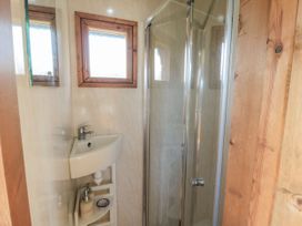 A bathroom with a sink, shower, and two windows at Honeysuckle Hut, Potto Grange Farm, Northallerton