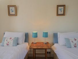 A bedroom with two beds and a table with lamps at Goulds Farmhouse in Milborne St Andrew