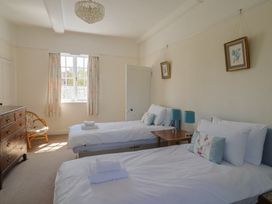 A bedroom with two beds, a dresser, and a chair at Goulds Farmhouse in Milborne St Andrew