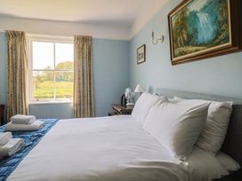 A bedroom with a bed, window, and fan at Goulds Farmhouse in Milborne St Andrew