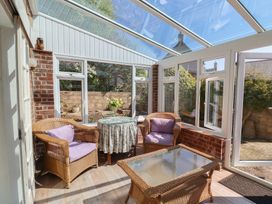 A conservatory with wicker furniture and a glass table at Goulds Farmhouse in Milborne St Andrew