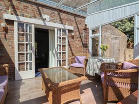 A conservatory with wicker furniture and a glass table at Goulds Farmhouse in Milborne St Andrew