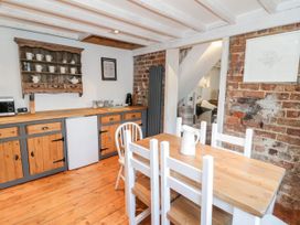 A kitchen with wooden cabinets and a dining table at Studio Bach in Beaumaris