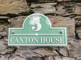 A house sign reading 5 Caxton House on a stone wall in Windermere