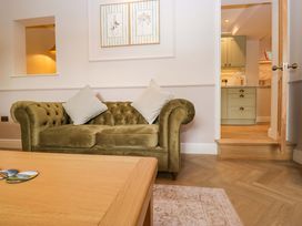 A living room with a green sofa and door leading to a kitchen at Flat 5 Caxton House Windermere