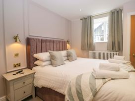 A bedroom with a bed, bedside table, and window at Flat 5 Caxton House in Windermere