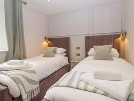 A bedroom with two single beds and a bedside table at Flat 5 Caxton House in Windermere