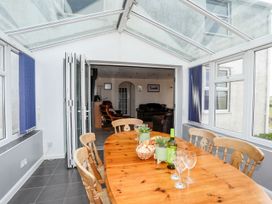 A conservatory with a wooden table and chairs at Bodlasan Groes Cottage Holyhead