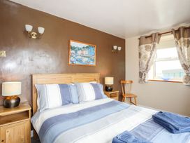 A bedroom with a bed and a painting at Bodlasan Groes Cottage in Holyhead