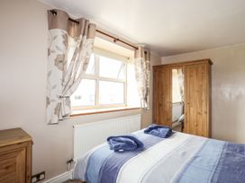 A bedroom with a bed and wardrobe at Bodlasan Groes Cottage in Holyhead