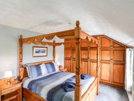 A bedroom with a four-poster bed and wooden wardrobe at Bodlasan Groes Cottage in Holyhead