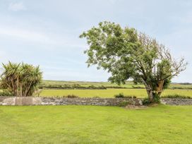 A garden with a tree and treehouse at Bodlasan Groes Cottage in Holyhead