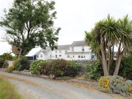An outdoor view of a building and treehouse at Bodlasan Groes Cottage in Holyhead
