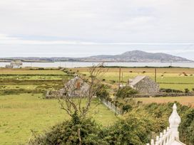 A view of fields and cows with houses near the ocean at Bodlasan Groes Cottage in Holyhead