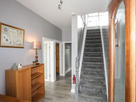 A hallway with a staircase and a bookshelf at Bodlasan Groes House, Holyhead