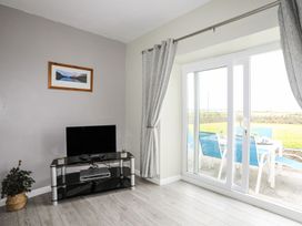 A living room with a television and sliding door at Bodlasan Groes House in Holyhead