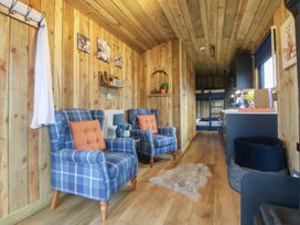 A living room with blue chairs and a kitchen area at The Suffolk in Knutsford