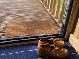 Shoes and a door mat by a sliding door at The Suffolk Hut, Lower Peover, Cheshire