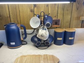A kitchen countertop with a kettle and a cup rack with mugs at The Suffolk Hut in Lower Peover, Cheshire
