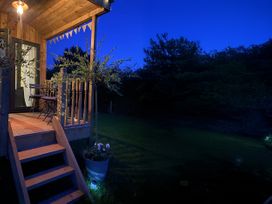 An outdoor porch with stairs, table, chairs, and light at The Suffolk Hut in Lower Peover, Cheshire