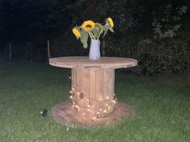 A wooden table with a vase of sunflowers at The Suffolk Hut in Lower Peover, Cheshire
