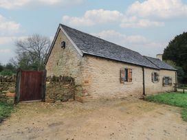 A cottage with a stone wall and wooden gate at The Forge in Broadwell near Stow-On-The-Wold