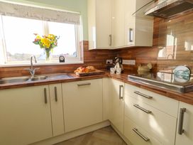 A kitchen with a sink, flowers on the window, and bread on a cutting board at 46 Chafeys Avenue 